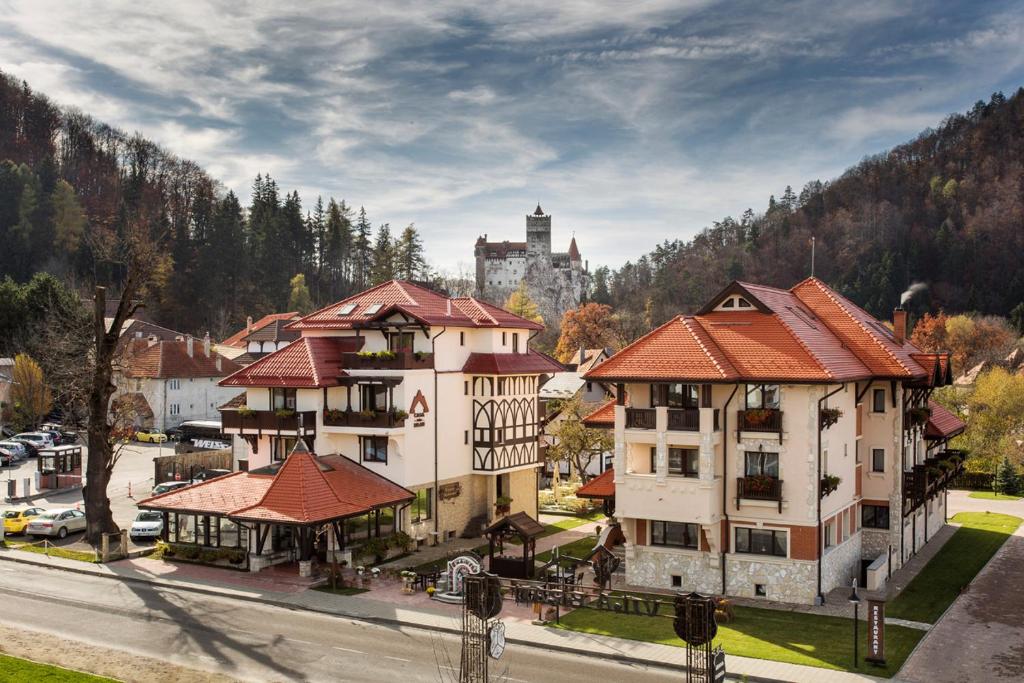 an aerial view of a town with a castle in the background at Casa Din Bran - Inn Center in Bran