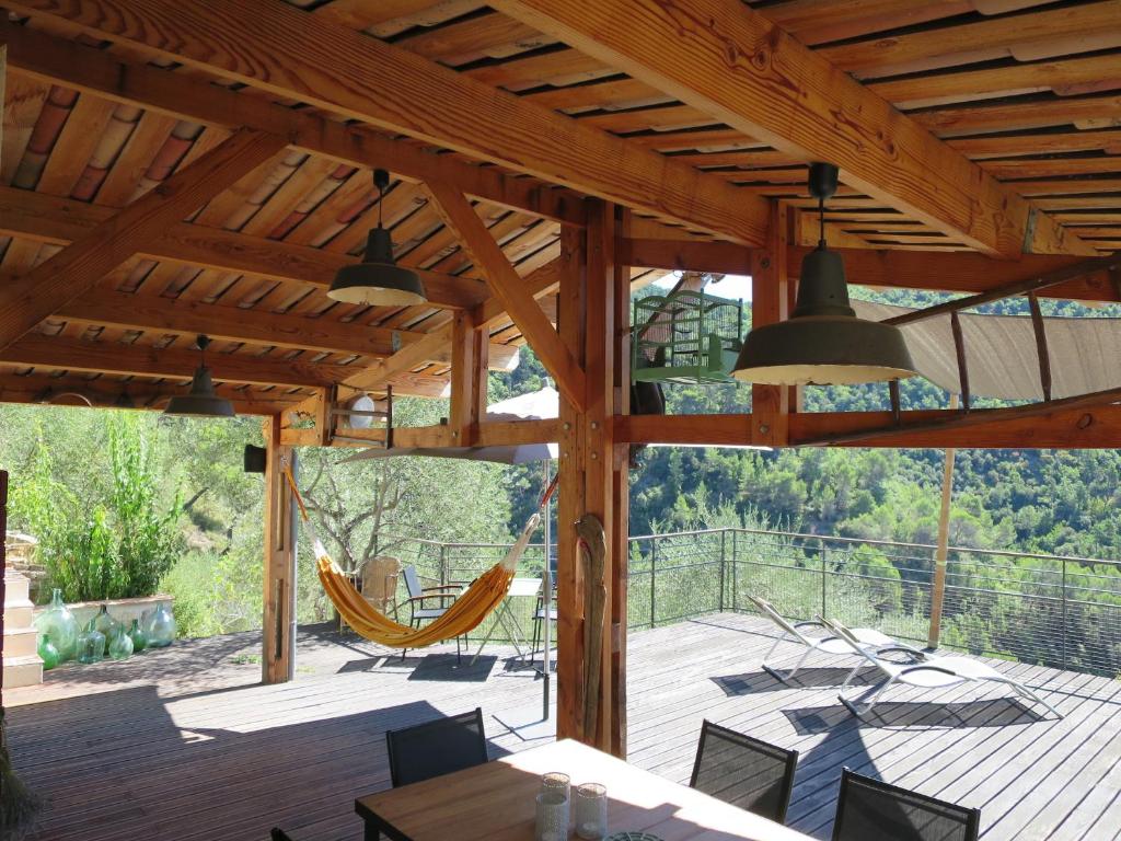 un patio con sillas y hamacas en una terraza de madera en Les Figaires, en LʼEscarène