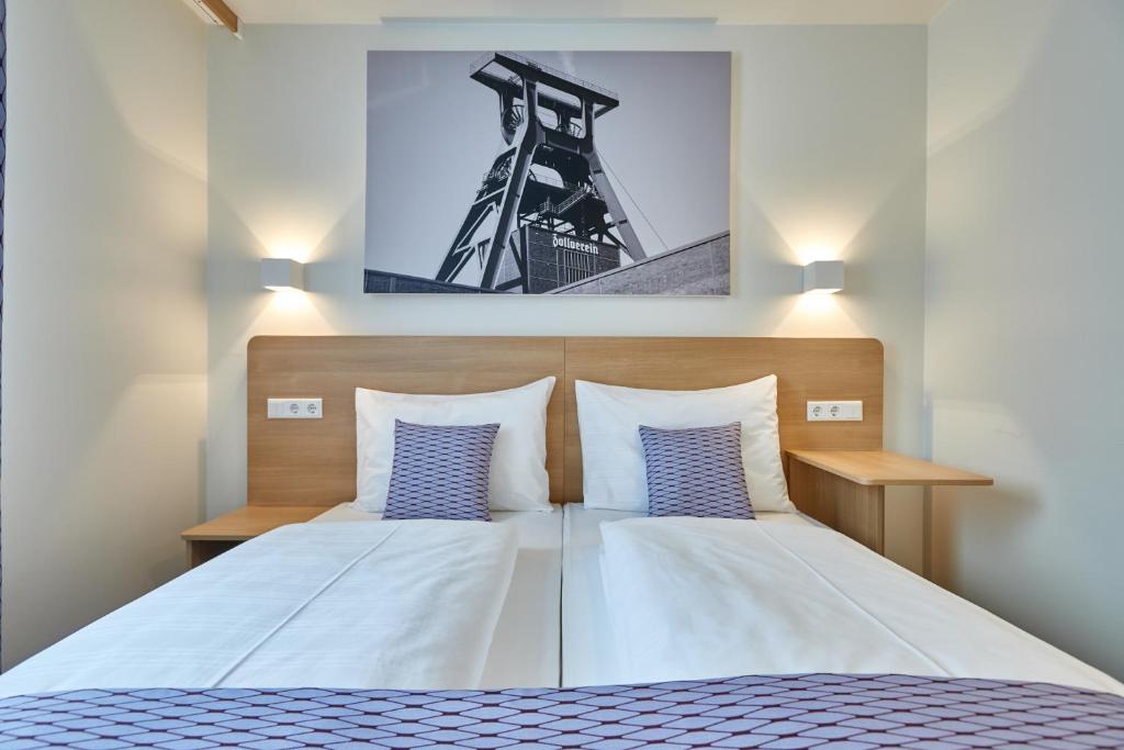 a bedroom with a bed with blue and white pillows at McDreams Hotel Essen in Essen