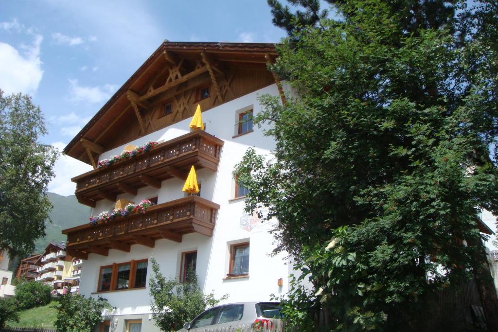 a white building with a wooden balcony at Pension Alpenrose in Serfaus