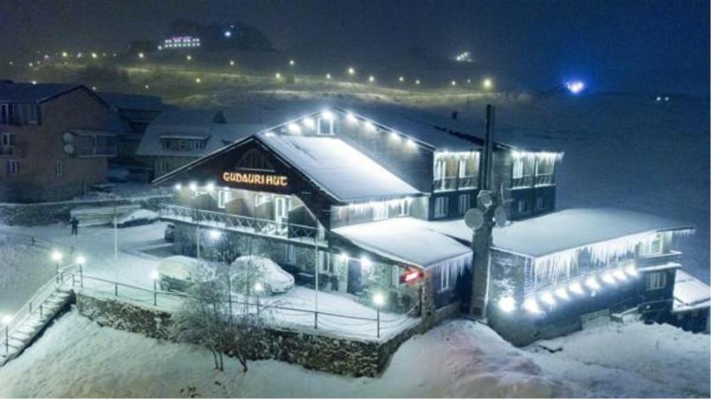 a building covered in snow at night with lights at Gudauri Hut Hotel in Gudauri
