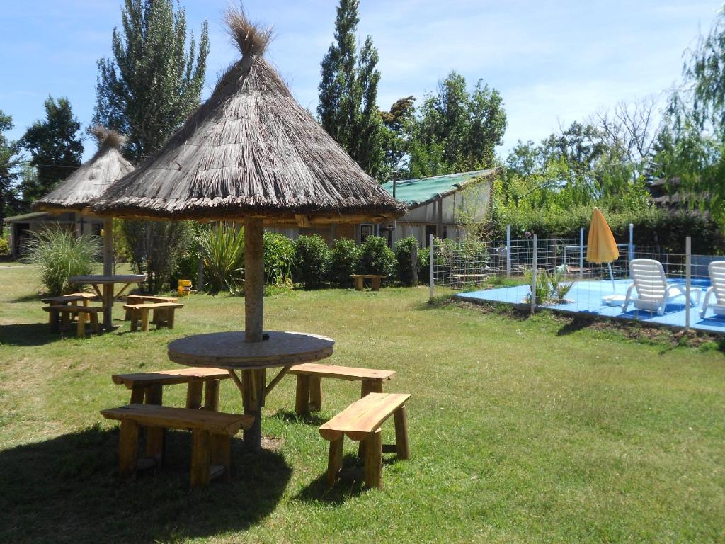 een picknicktafel en banken met een rieten paraplu bij Amanecer en Cuyo in San Rafael