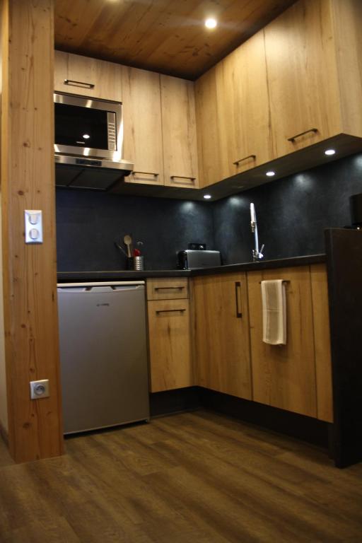 eine Küche mit Holzschränken und einem Kühlschrank aus Edelstahl in der Unterkunft Alpage 1 in Avoriaz