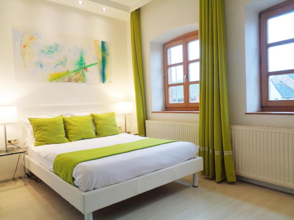 a bedroom with a bed with green sheets and windows at Hotel Apartment Puell in Eimersleben