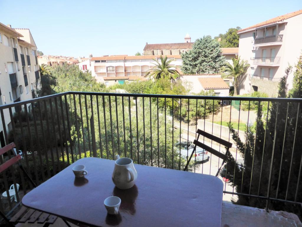 une table avec deux tasses et un vase sur un balcon dans l'établissement 4VSE-COB279 Appartement proche plage avec parking privé, à Collioure