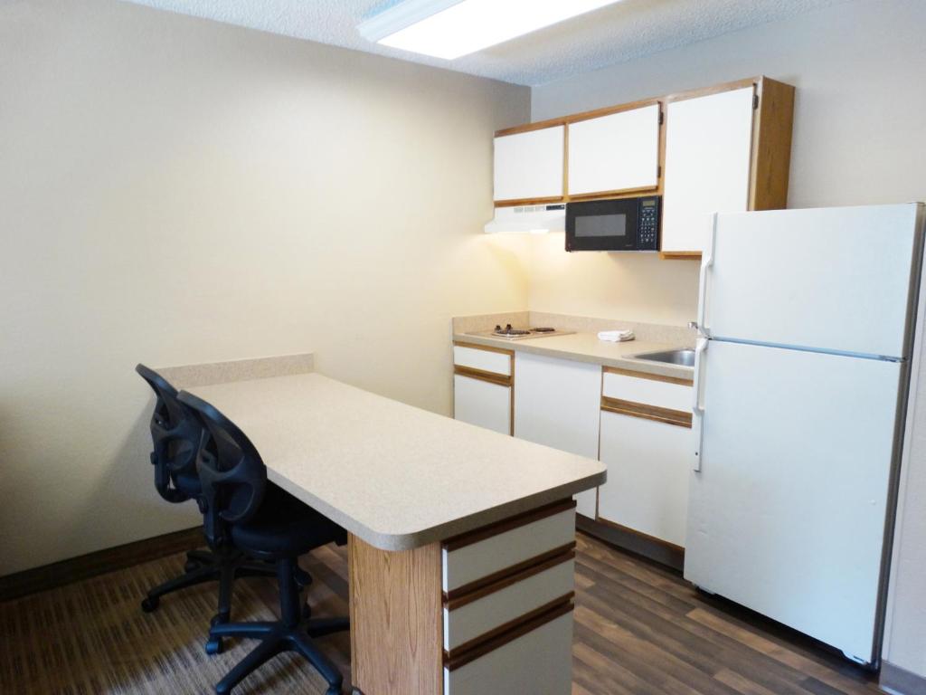 a small kitchen with a white refrigerator and a desk at Extended Stay America Select Suites - Orlando - Lake Mary - 1040 Greenwood Blvd in Lake Mary