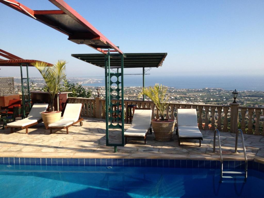 een zwembad met stoelen en uitzicht op de stad bij Villa Aphrodite in Peyia