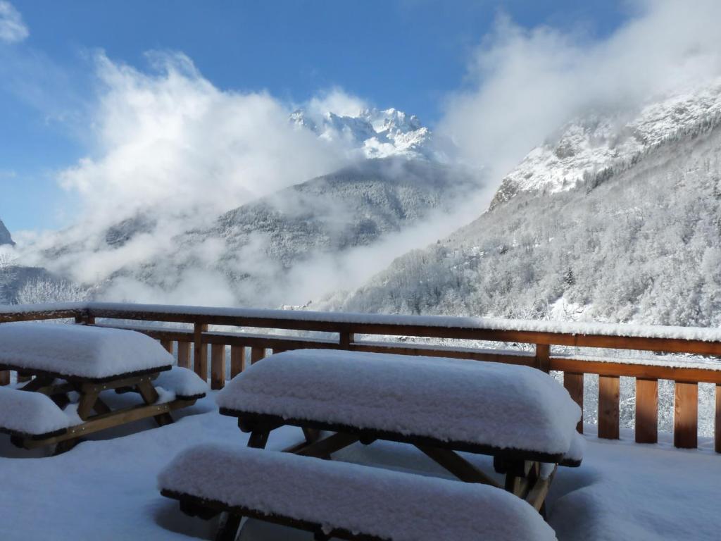 Deux tables de pique-nique recouvertes de neige devant une montagne dans l'établissement Les Petites Marmottes, à Vaujany