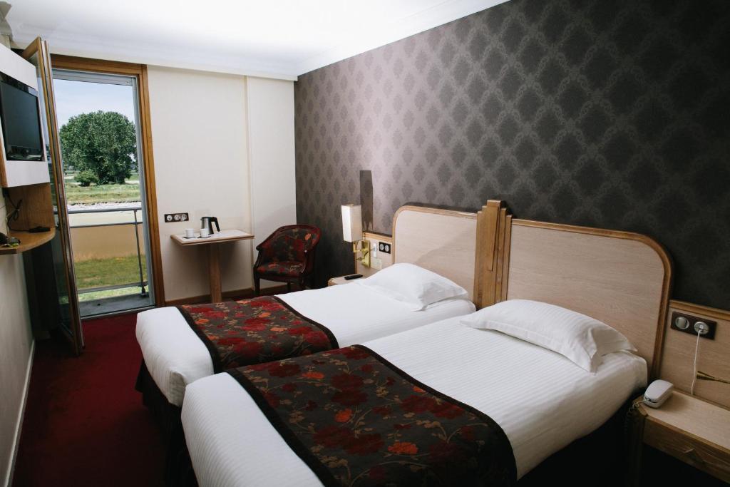 a hotel room with two beds and a window at Le Relais Du Roy in Le Mont Saint Michel