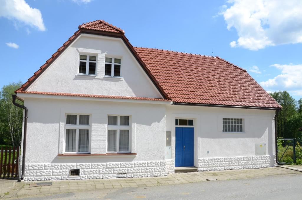 Biały dom z czerwonym dachem i niebieskimi drzwiami w obiekcie Station House Loft Apartment w mieście Obrataň