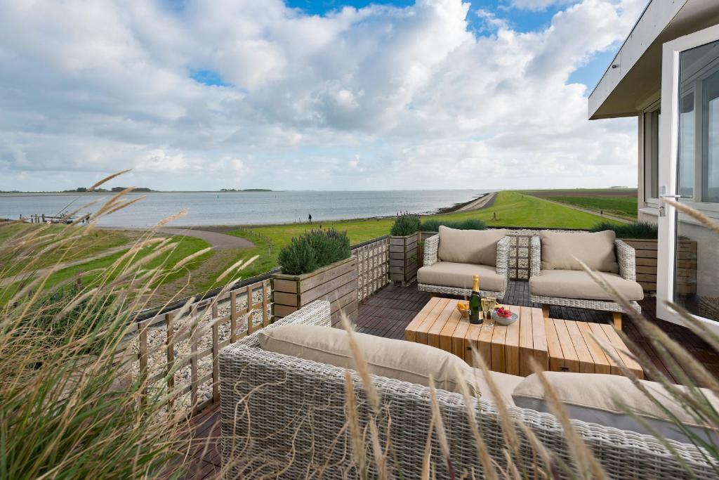 a patio with a couch and a table and the ocean at Appartement Zilte Lucht in Wilhelminadorp