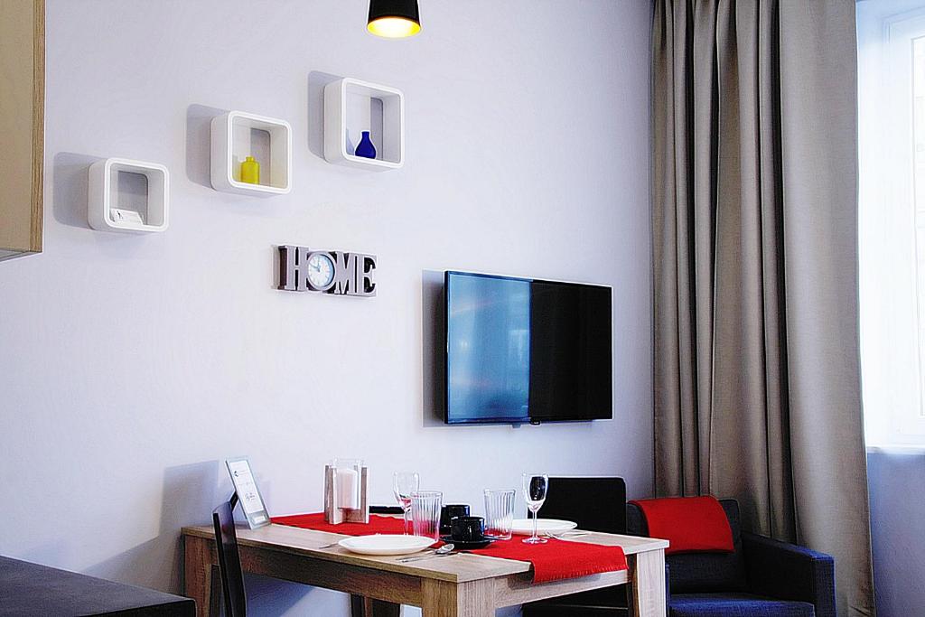 a room with a table and a tv on the wall at Apartment III GrayFor2 Old Town Kraków in Krakow