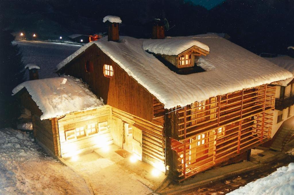 uma casa de madeira coberta de neve à noite em Hotel Garni Plueme em Sauris