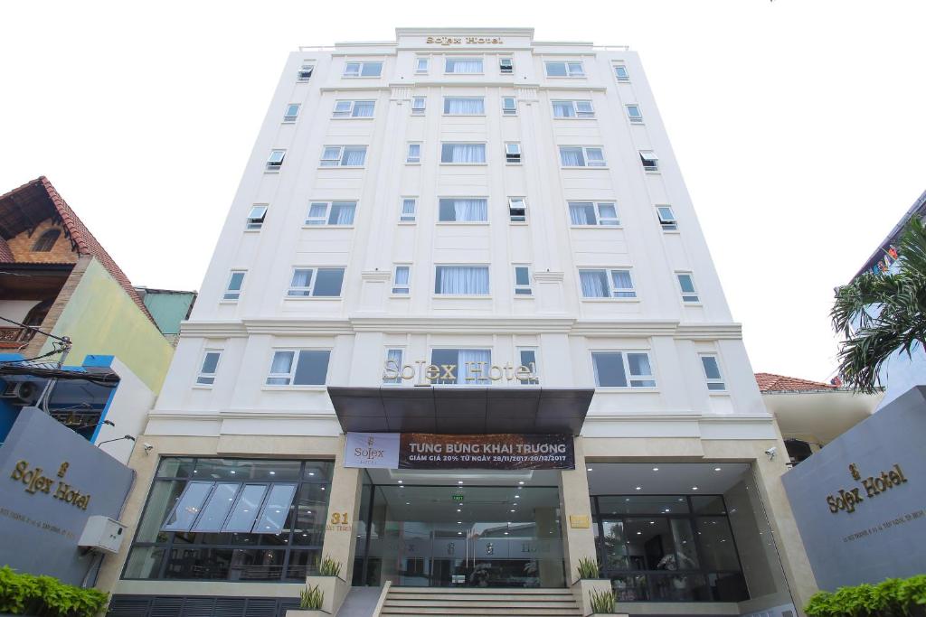 un edificio blanco alto con escaleras delante en SoLex Hotel en Ho Chi Minh