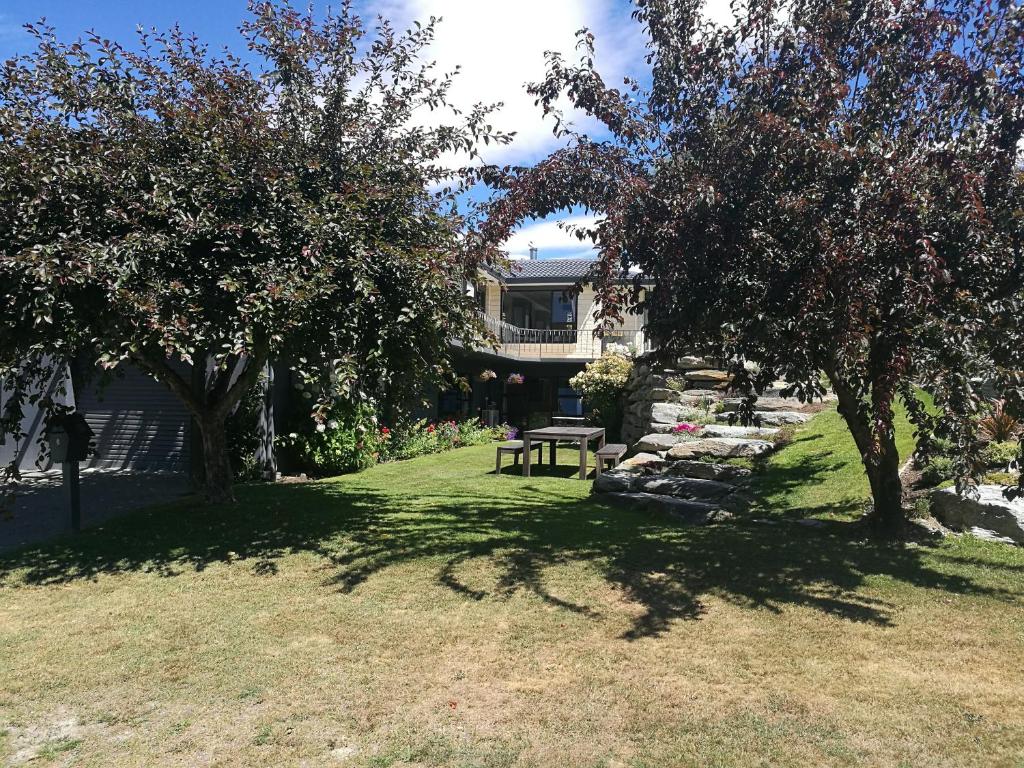 a park with a picnic table and trees in front of a house at Park to Mountains Apartment in Arrowtown