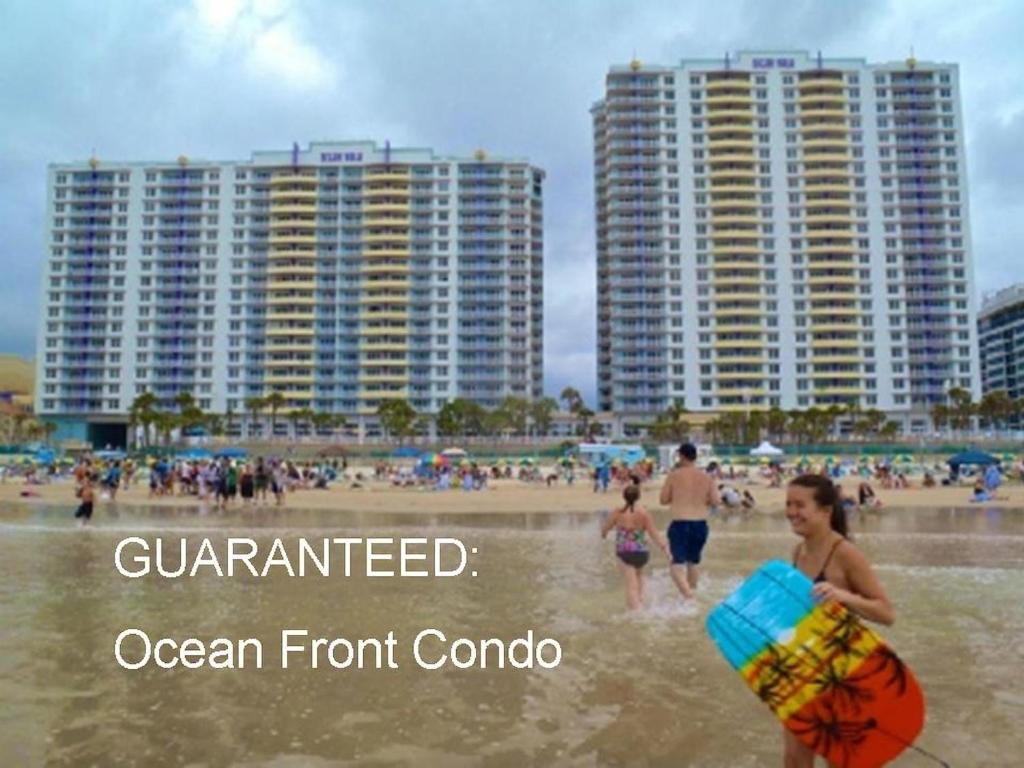 een groep mensen op een strand met gebouwen bij Ocean Walk Resort 911i - 828 in Daytona Beach