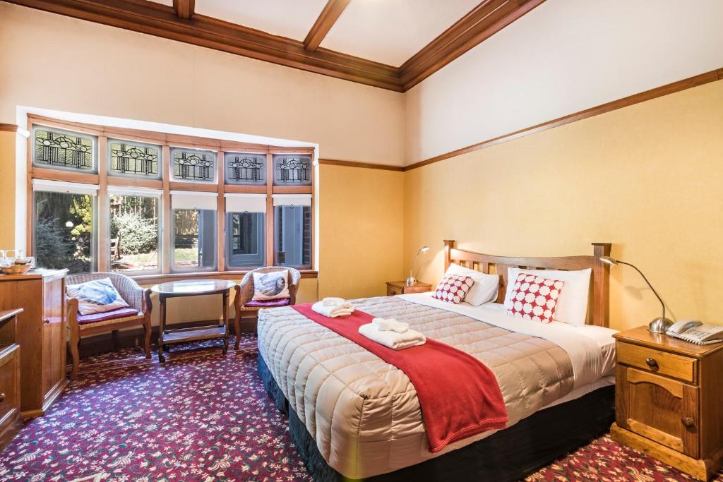 a bedroom with a bed and a desk and windows at Halswell Lodge in Wellington