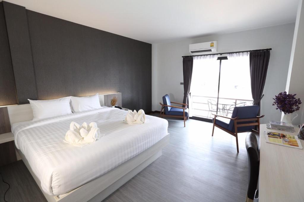 a bedroom with a white bed with two white flowers on it at Socool Grand Hotel in Nang Rong