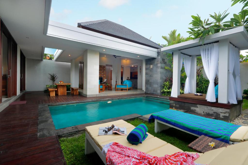 un patio trasero con piscina y una casa en Vansari Serenity Villa, en Seminyak