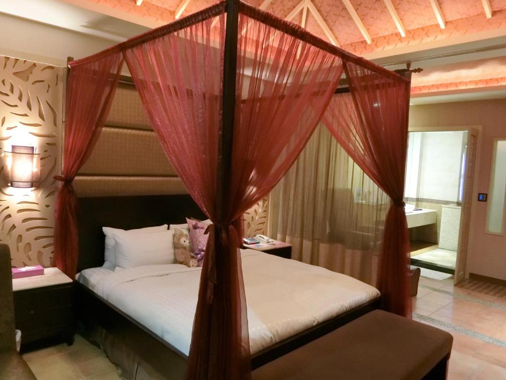 a bedroom with a canopy bed with red drapes at Mambo Impression Motel in Chaozhou