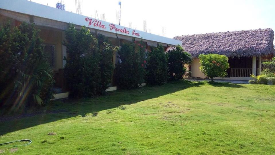 a building with a grass yard in front of it at Villa Peralta Inn in Donsol