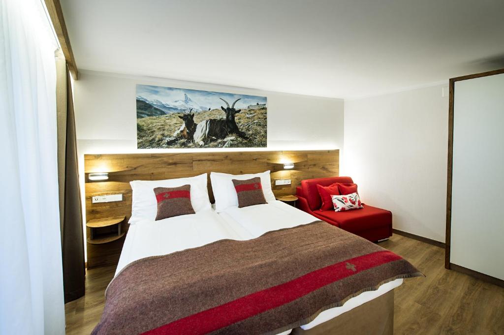 a bedroom with a large bed and a red chair at Apartments Butterfly Zermatt in Zermatt