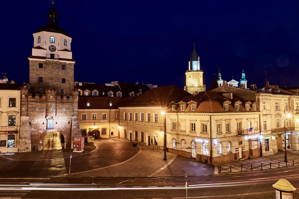 un grand bâtiment avec deux tours et une rue la nuit dans l'établissement Carmelito, à Lublin