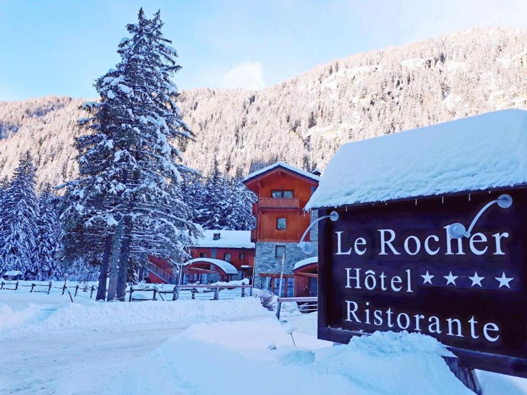 a hotel sign in the snow in front of a building at Le Rocher Hotel in Champoluc