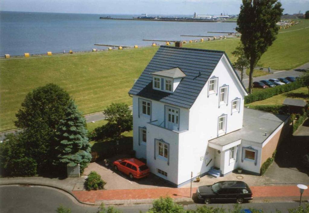 ein weißes Haus mit einem roten Auto davor in der Unterkunft Haus am Meer in Cuxhaven