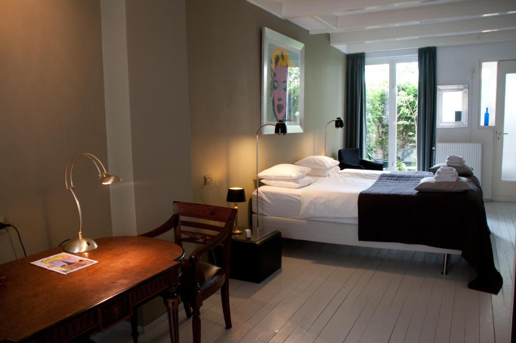 a bedroom with a bed and a table and a desk at Bed & Breakfast WestViolet in Amsterdam