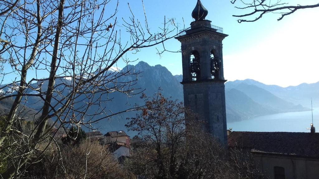 uma torre do relógio com vista para um lago e montanhas em La Casa delle Fate em Solto Collina