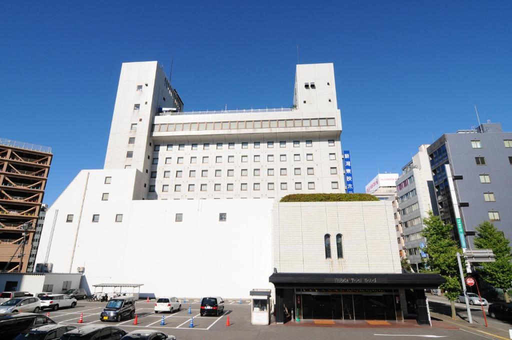 a large white building with cars parked in a parking lot at Niigata Toei Hotel in Niigata
