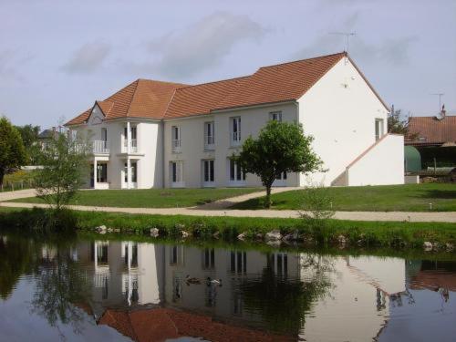 a white house with a reflection in a body of water at L'Orée des Châteaux in Bracieux