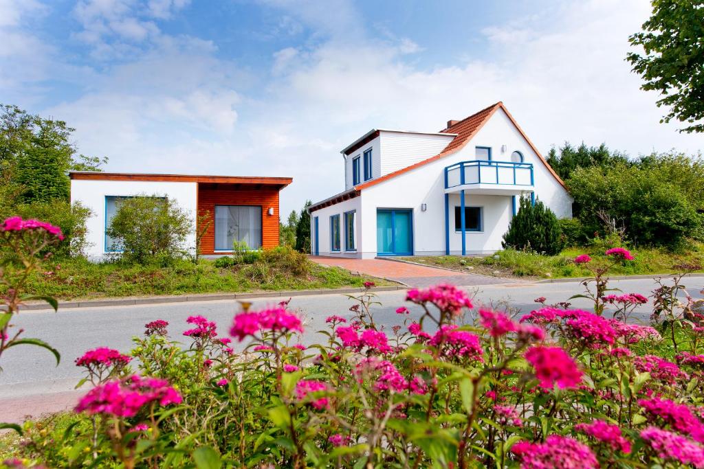 ein Haus mit rosa Blumen vor einer Straße in der Unterkunft Ferienwohnungen Ostrea & Rugia in Breege