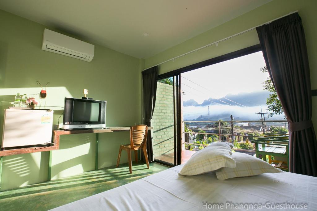 Home Phang-Nga Guesthouse في فانجنجا: غرفة نوم مع سرير وبلكونة مع تلفزيون