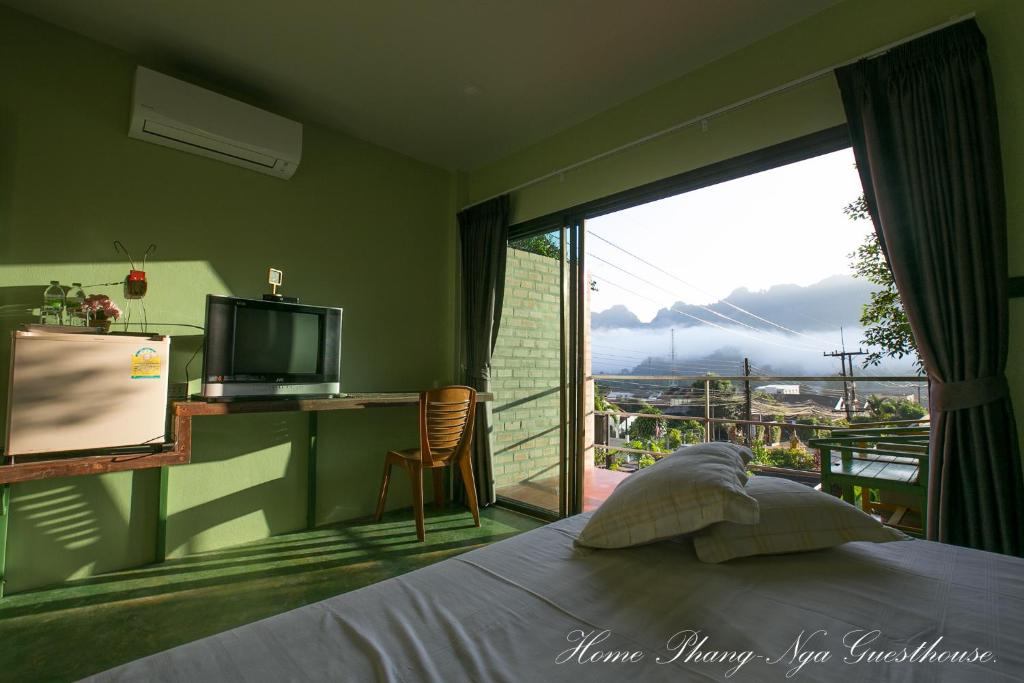 a bedroom with a bed and a television and a balcony at Home Phang-Nga Guesthouse in Phangnga