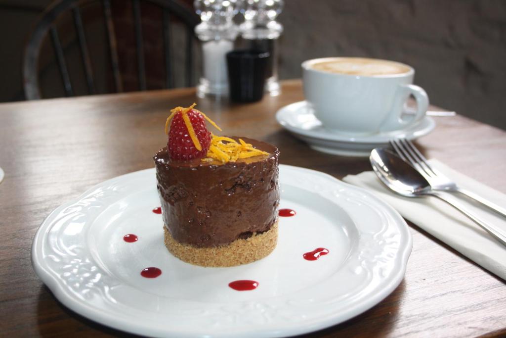 a piece of chocolate cake on a plate with a cup of coffee at The Three Horseshoes in Warham