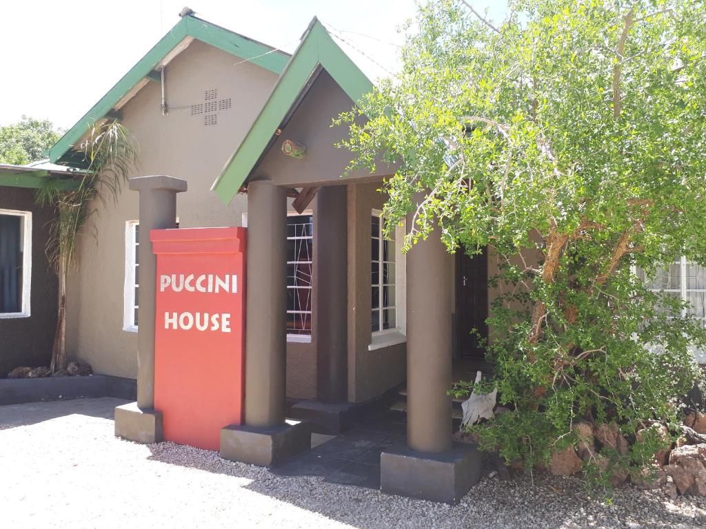 una casa con un cartel de la casa pucán delante de ella en Puccini House, en Windhoek