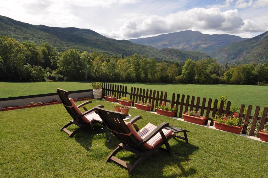 two chairs sitting on a lawn with mountains in the background at Hotel Selba d'Ansils in Benasque