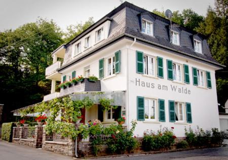 a large white house with green shutters and flowers at Pension "Haus am Walde" Brodenbach, Mosel in Brodenbach