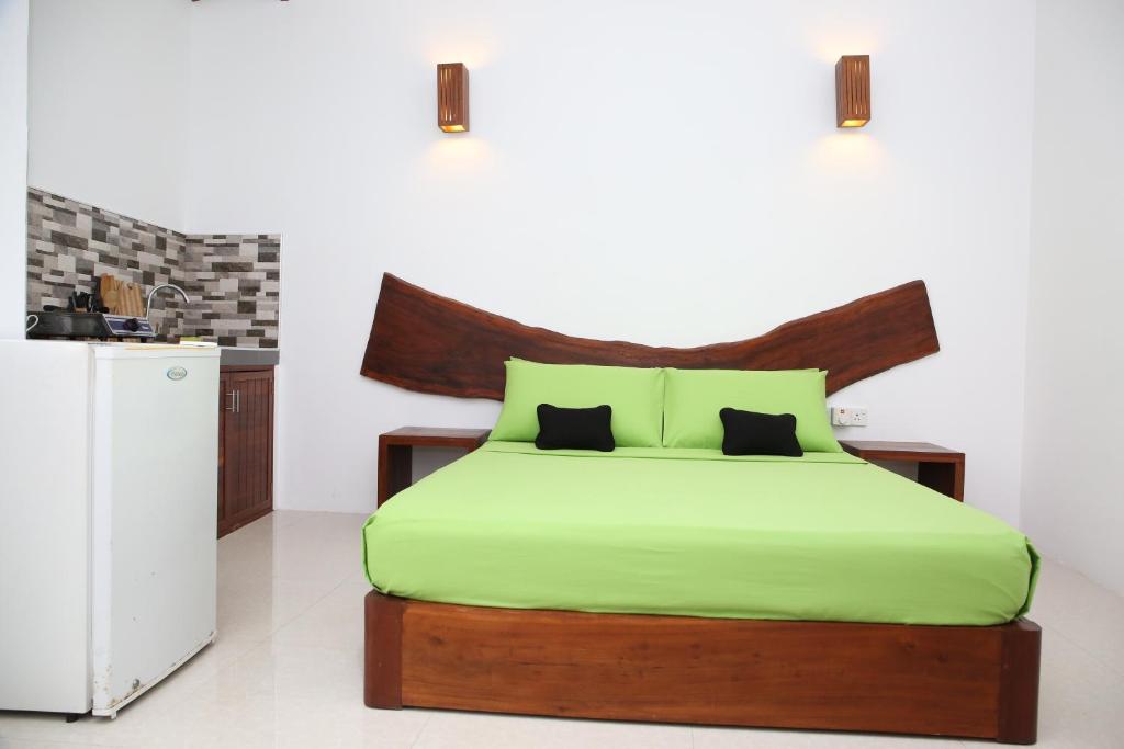1 dormitorio con 1 cama con sábanas verdes y nevera en THE CLASSIC-Hostel-apartment-Standard Room en Weligama