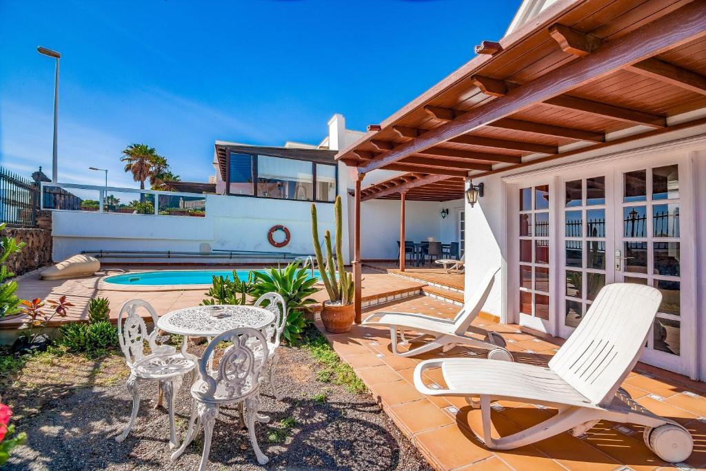 a patio with chairs and a table and a pool at Villa Tías in Tías