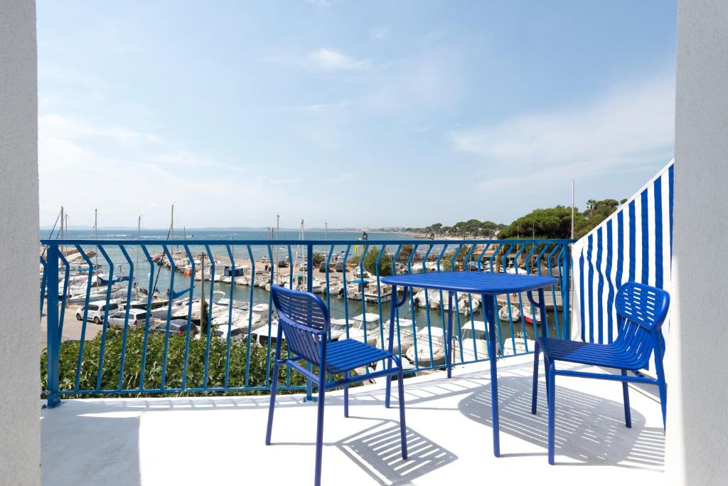 two chairs and a table on a balcony with a view of a harbor at Hôtel La Reine Jane in Hyères