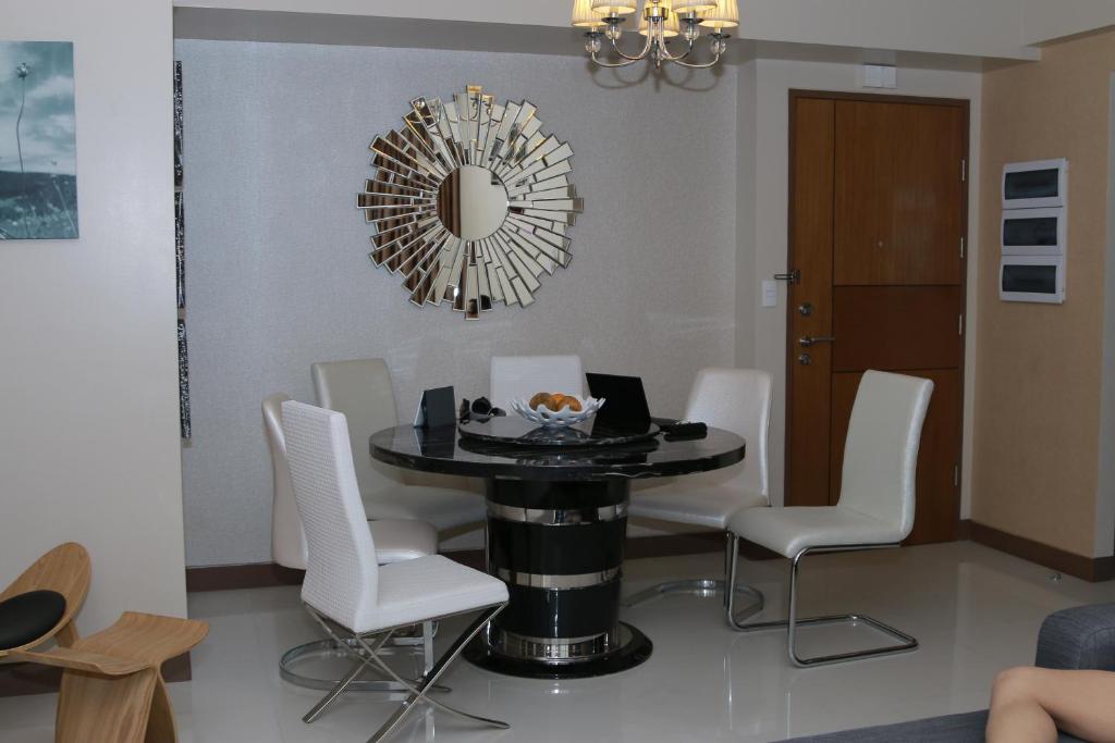 ein Esszimmer mit einem Tisch, Stühlen und einem Spiegel in der Unterkunft De Luxe 7QRS in Manila