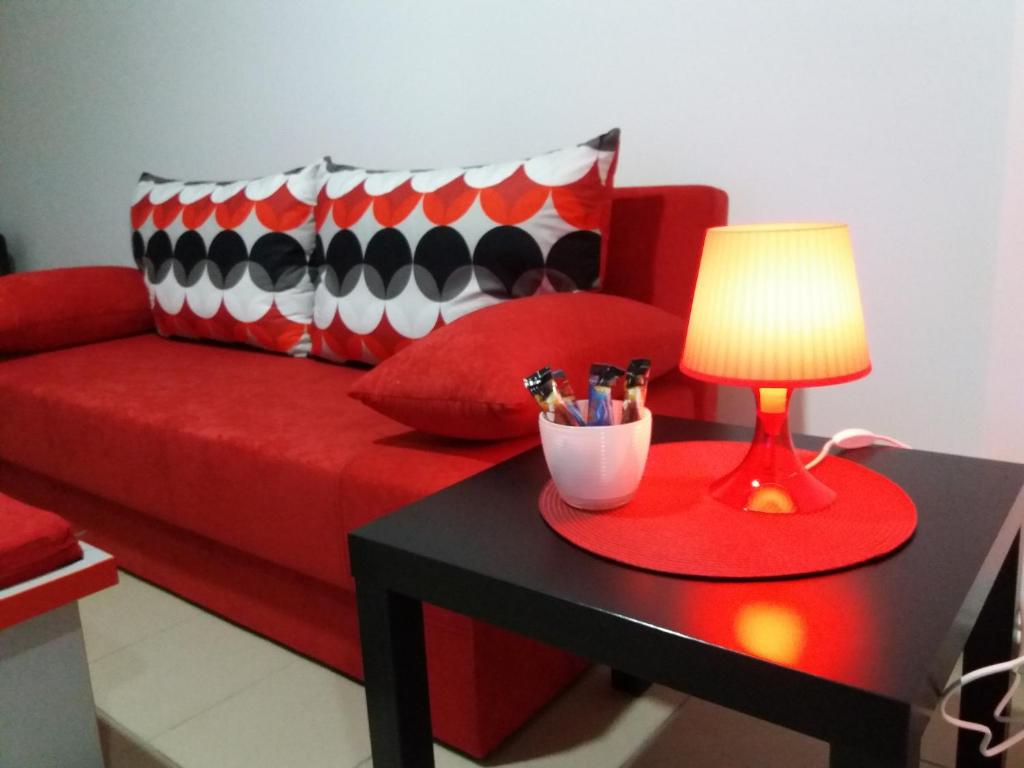 un sofá rojo con una mesa con una lámpara. en Dody Apartmani en Leskovac