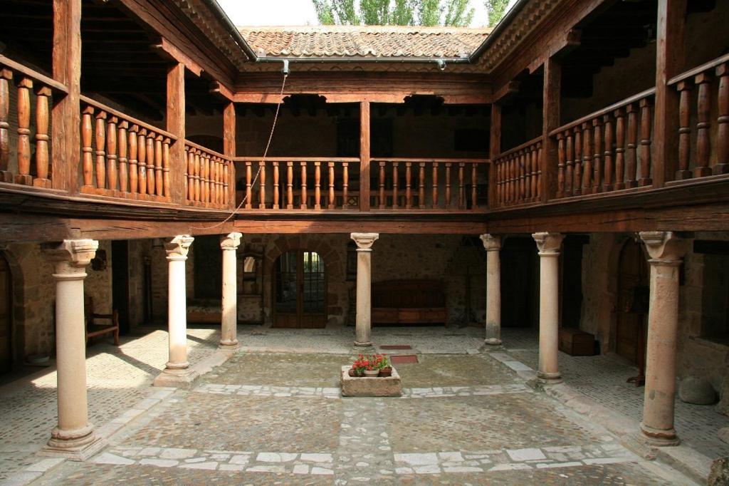 Habitación con balcón y vistas al interior de un gran edificio de madera. en Posada de San Millán en Sepúlveda