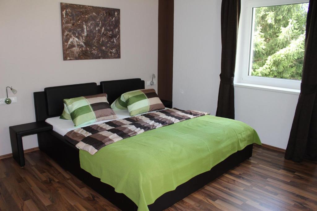 1 dormitorio con 1 cama con manta verde y ventana en Ferienwohnungen Maurer, en Umhausen