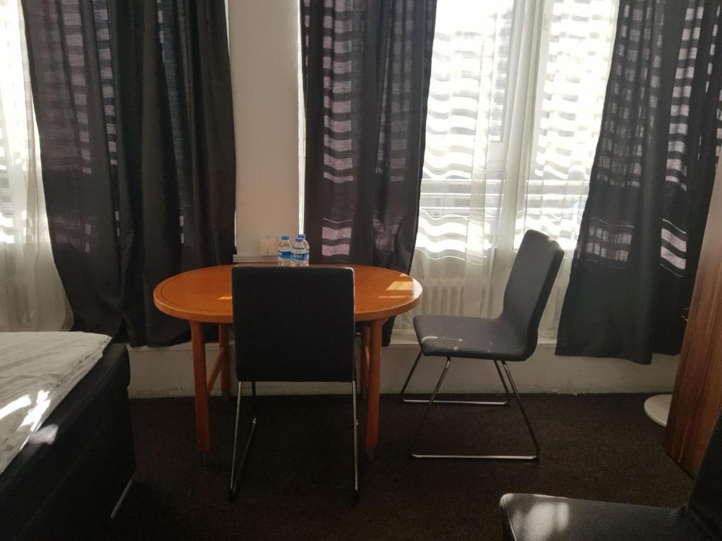 a dining room table and two chairs in front of a window at Hotel Wandsbek Hamburg in Hamburg