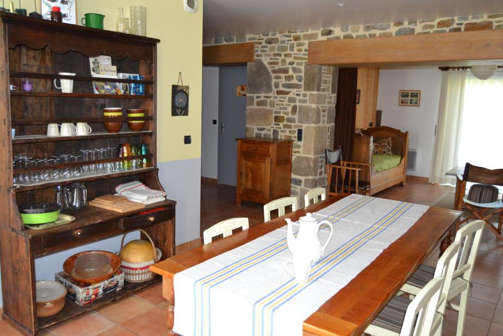 Gîtes Les Salicornes في Dragey: غرفة طعام مع طاولة وجدار حجري