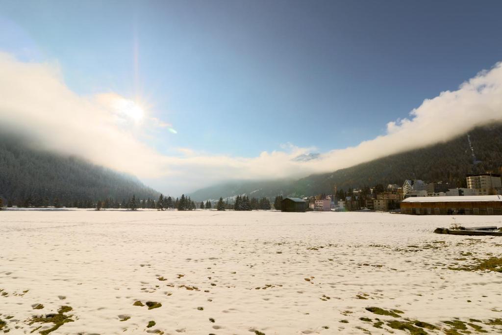 un campo cubierto de nieve con una ciudad al fondo en Dischmastrasse - Vonwyl, en Davos
